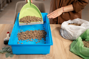 Cleaning rabbit cage tray using green dustpan for pellets