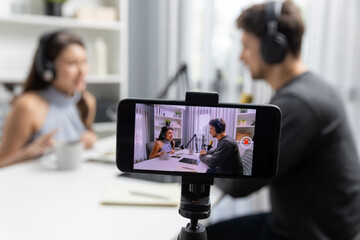 Focus on smartphone recording with blurry host channel broadcasters background making advice...