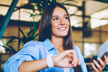 Positive successful hipster girl checking notification and gps tracking on electronic smartwatch,...