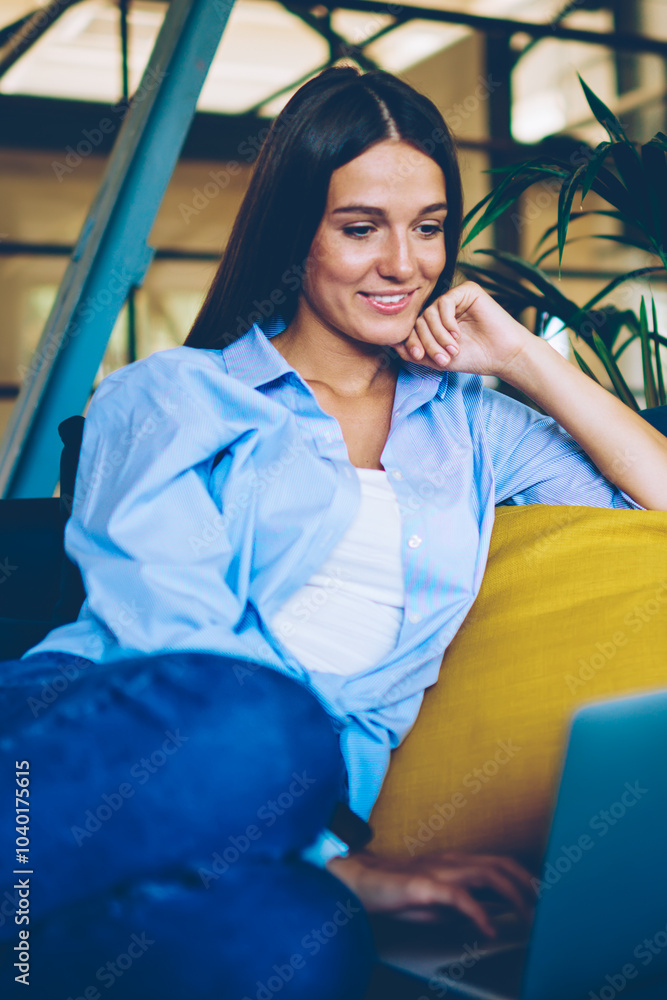 Poster positive smiling hipster girl searching funny movie for watching using modern laptop device indoors,