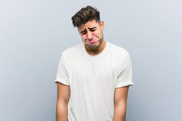 Obraz premium Young man expressing deep sadness and frustration while standing in a minimalistic space, conveying a sense of emotional struggle and vulnerability