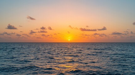 Obraz premium A vibrant orange and pink sunset over the ocean with light clouds.