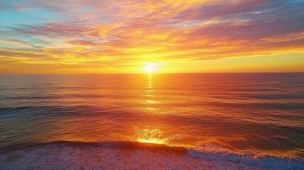 Fototapeta premium A vibrant sunset over the ocean, casting a warm glow on the water and the breaking waves.