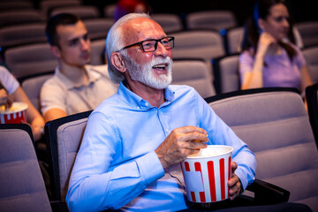 Older man enjoying retirement in the cinema by watching a movie.