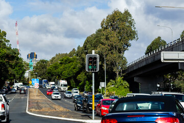 Green traffic lights at city intersection with busy road full of cars