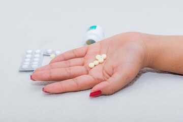 A woman's hand on a bed with some pills, indicating an overdose.