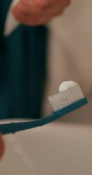The man is going to brush his teeth. He squeezes the toothpaste onto the brush. Close-up of his hands, an unrecognizable person