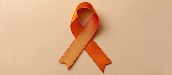 Top view of an orange awareness ribbon on a beige backdrop with room for text ideal for a copy space image