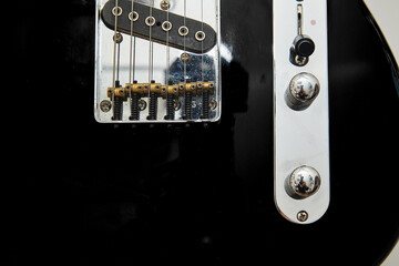 Details of a vintage American electric guitar, black with chrome and maple neck