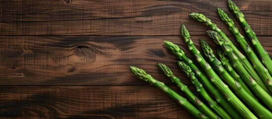 Wooden table showcasing fresh green asparagus stems from above with copy space image available for text