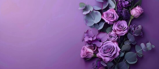 Purple roses and eucalyptus in a flower bouquet adorned with a ribbon on a purple backdrop ideal for a copy space image from a top view