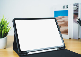 Tablet with blank screen on wooden table. Office supplies, Books, Indoor plants, on wooden table and white wall. Space for copying your text, Workspace and copy space, Desk with office supplies.