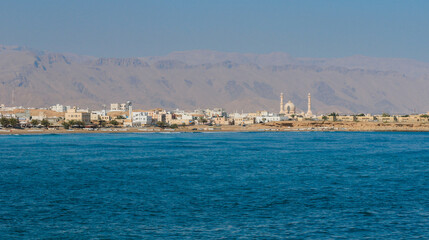 A view of Sur Oman showcasing coastal beauty and distant mountains under clear blue sky