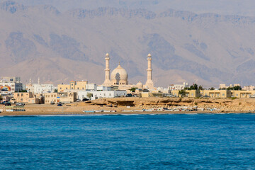 A serene view of Sur’s coastline with its iconic mosque and vibrant local community beside the tranquil sea