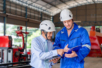 a young male caucasian technician holding paper document is consulting a senior man expertise manager the problem of maintenance welding robot machine at robot factory