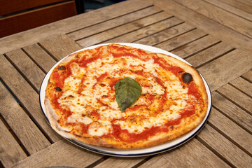 A delicious Margarita pizza topped with mozzarella cheese and red tomato sauce placed on a wooden table