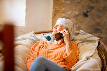 Happy senior woman talking on phone in cozy home setting