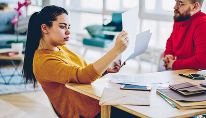 Pensive woman analyzing information from financial report  planning online business with husband at home interior, thoughtful colleagues concentrated on making solution for project sitting at desktop
