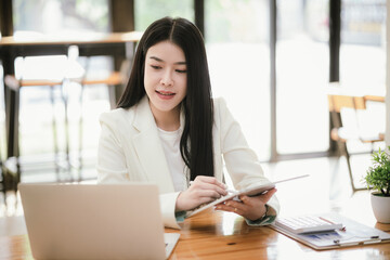 Beautiful Asian businesswoman focused on reviewing documents in a modern office.