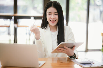 Beautiful Asian businesswoman focused on reviewing documents in a modern office.