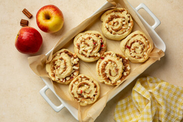 Cooking Homemade Rolls Buns with apples and cinnamon. Uncooked, raw dought. Top view, flat lay, beige background.