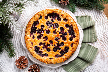 Christmas pie with mixed berry and almond crust, or tart with snawflakes decoration. Homemade. Winter New Year festive bakery, wooden white table surface, above.