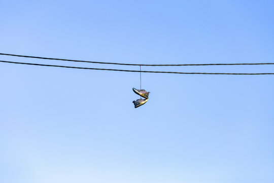 Pair of shoes with laces tied thrown over power line in urban neighbourhood