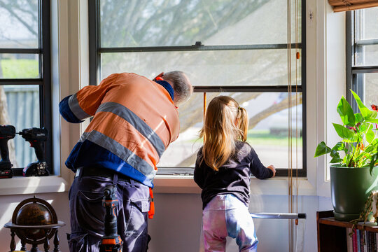 Little girl helping grandfather fix the window at home