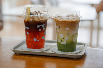 Close up glass of ice matcha green tea with espresso , iced tea honey lemon on wooden table of a coffee shop summer terrace, menu photography.