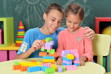 Little brother and sister assemble a construction set at home