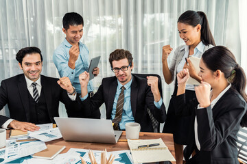 Group of happy businesspeople in celebratory gesture and successful efficient teamwork. Diverse race office worker celebrate after made progress on marketing planning in corporate office. Meticulous