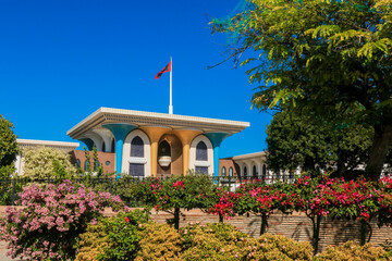 The stunning architecture of Sultans Palace in Muscat surrounded by vibrant flowers under a clear...