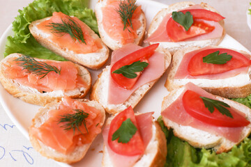 Appetizer sandwiches with salmon and dill. Small bread slices with ham. Party snacks perfect for a banquet. Delicious homemade treats for any gathering. Catering company food. Finger food buffet.