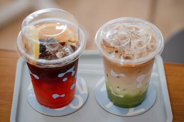 Close up glass of ice matcha green tea with espresso , iced tea honey lemon on wooden table of a coffee shop summer terrace, menu photography.