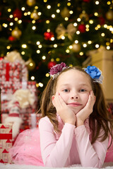 A little girl lies in the living room near the Christmas tree , New Year's magic