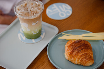 croissant in plate on the wooden table at coffee shop.
