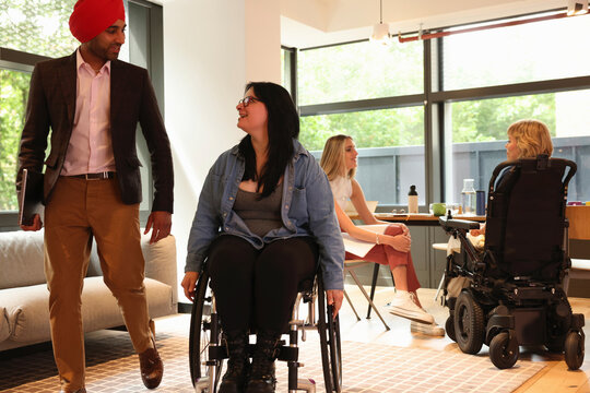 Businessman wearing Sikh turban and businesswoman on wheelchair in office