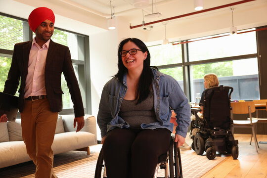 Businessman wearing Sikh turban and businesswoman on wheelchair in office