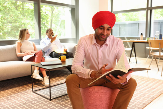 Businessman wearing Sikh turban reading document in office