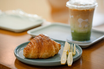 croissant in plate on the wooden table at coffee shop.

