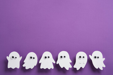 Adorable white ghost figures with googly eyes on a purple background, fun and spooky Halloween banner with copy space