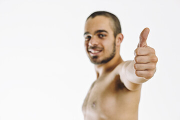 Shirtless man making thumbs up sign on white background