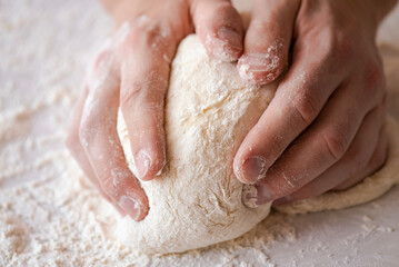 Close-up of baker making dough, person knead dough on table