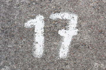Number 17 painted on concrete. Numbered parking spot. Marked on ground with white paint. Parking...