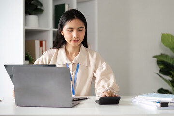 Female Accountant Analyzing Financial Management Documents at Modern Office Desk with Laptop and Calculator