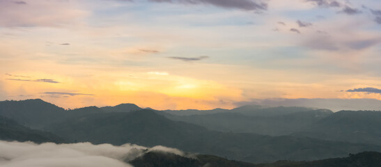 Sunrise sky on mountains layer and mist clouds in the morning,Horizon Nature Golden hour with Sunset sky Landscape with orange, yellow sunlight over peak mountain in green trees forest