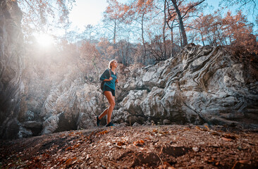 Active lifestyle. Trekking and hiking. Young woman with rucksack in the rocks forest.