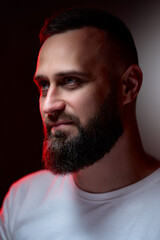 Fototapeta premium Studio portrait with colorful light of young handsome bearded man.