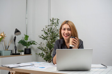 Fototapeta premium Business Woman Working on Document at Desk with Laptop and Coffee in Modern Office Setting