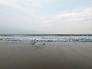 A serene evening at Rushikonda Beach, in Andhra Pradesh, India, with soft golden hues from the setting sun reflecting on the calm, blue waters.